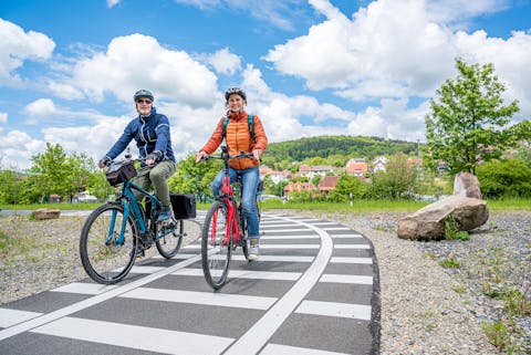 Frau und Mann fahren auf Rädern den Bahnradweg