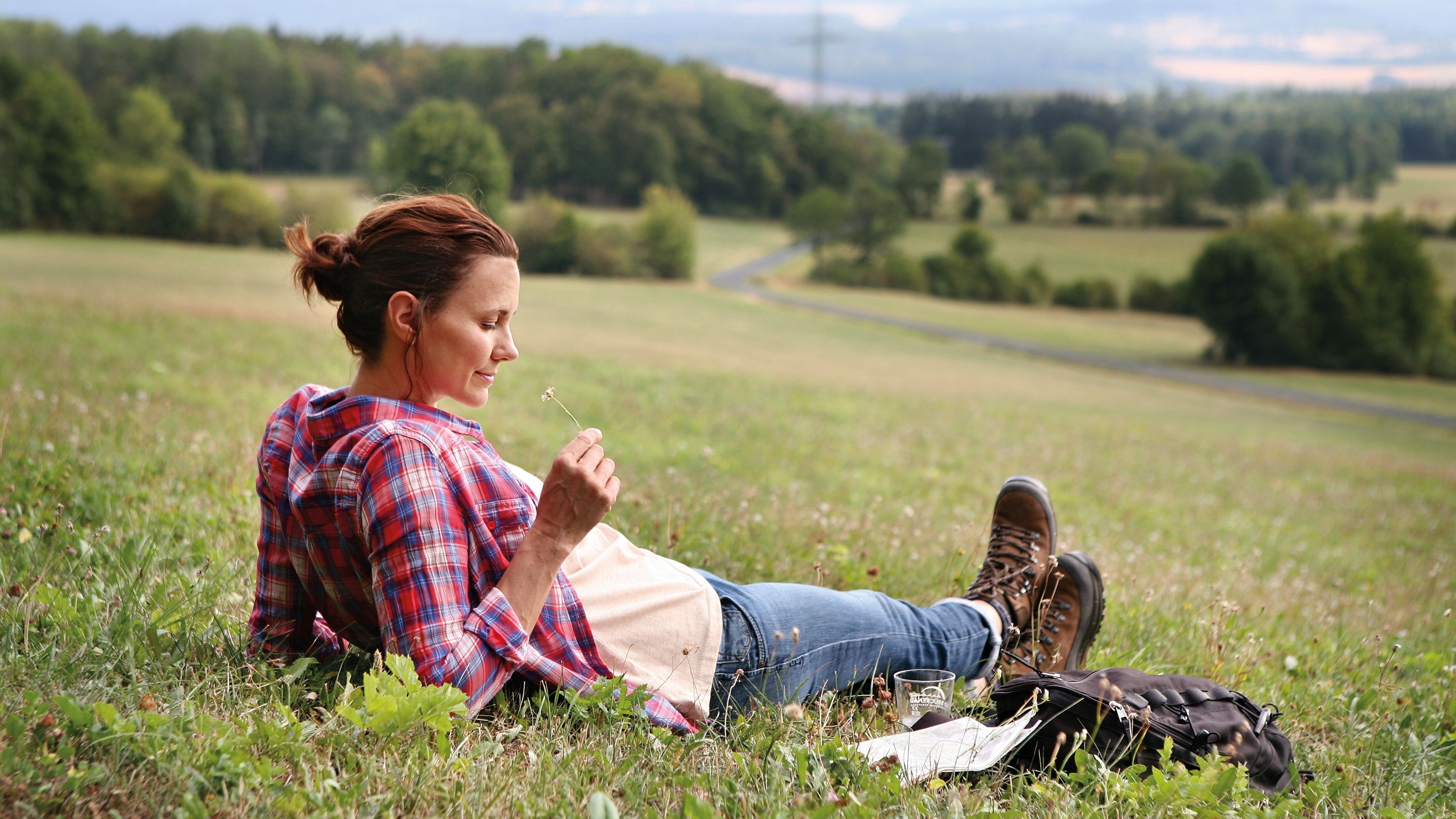 Eine Wanderin legt eine Pause auf einer Wiese ein